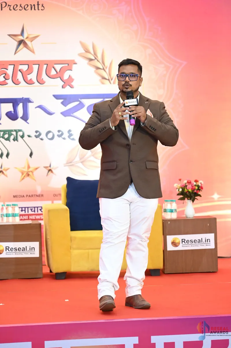 Nikhil Gadkarr speaking with a microphone at the Maharashtra Udyog Ratna ceremony